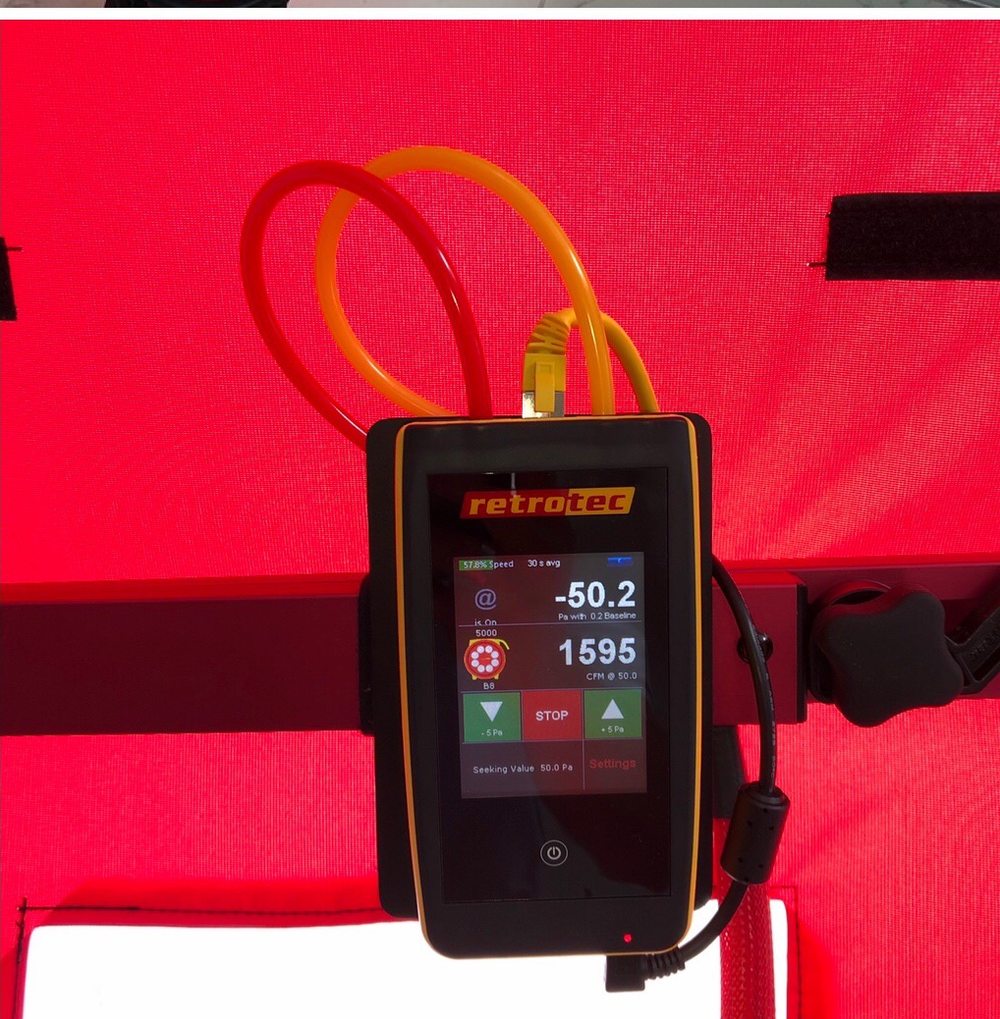 Blower door manometer reading negative 50.2 pascals and 1,595 CFM during an air leakage test.