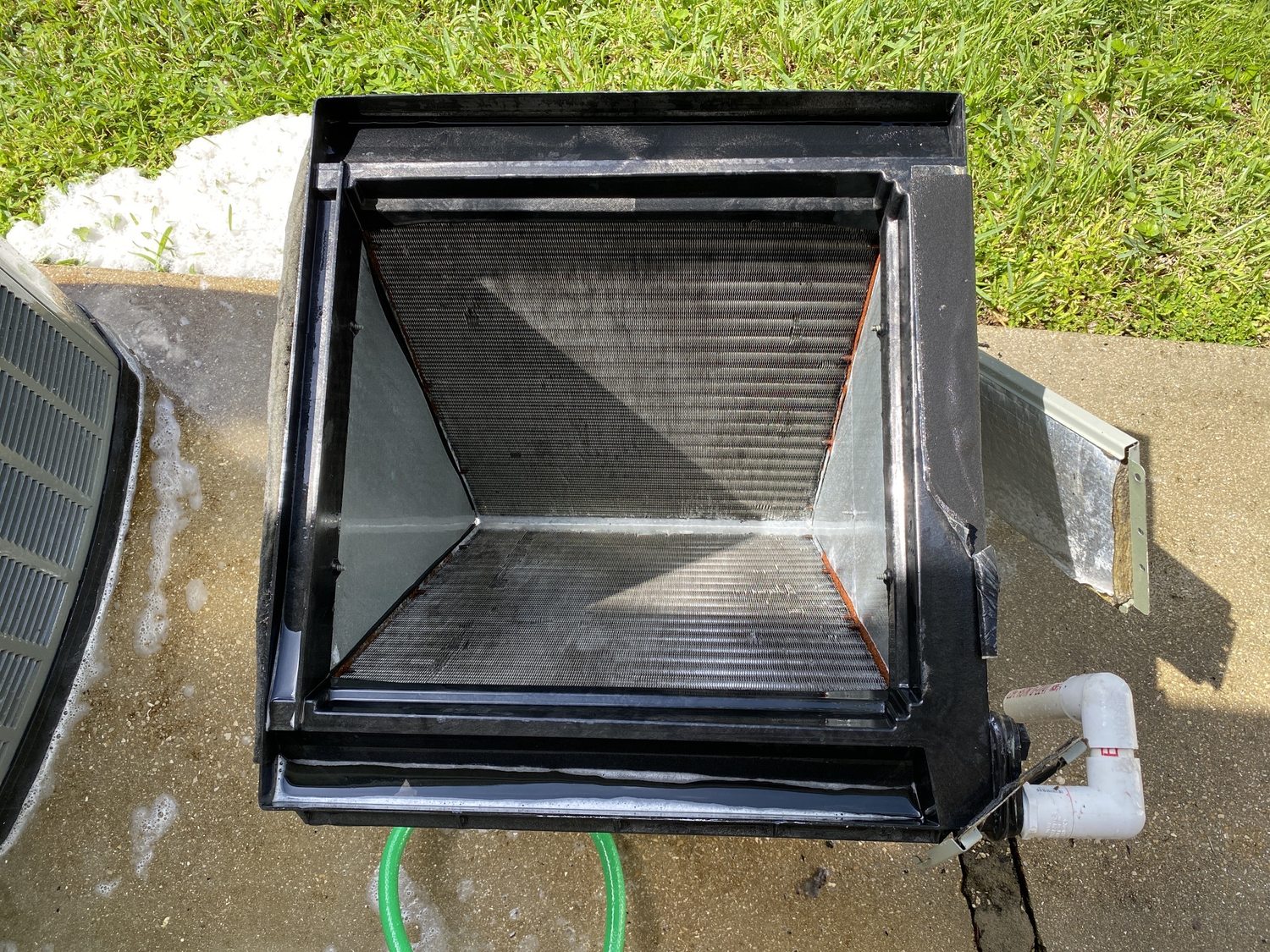 Evaporator coil fully cleaned and rinsed, drying on the driveway before reinstallation.