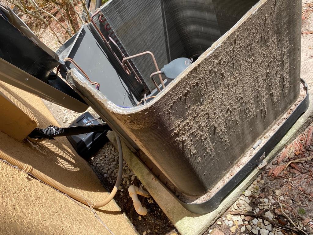 Condenser coil caked with a thick felt of dust and lint before cleaning.