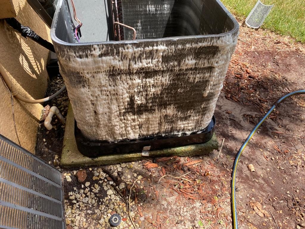 Condenser coil mid-cleaning, foam lifting years of buildup out of the fins.