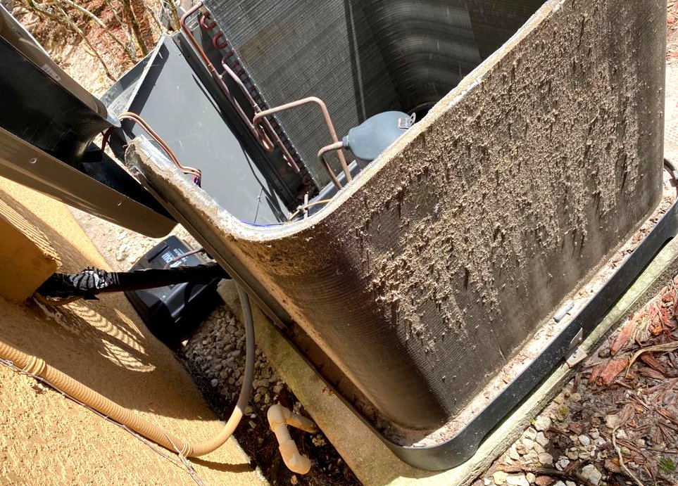 Condenser coil face caked with a thick felt of dust and lint before cleaning.