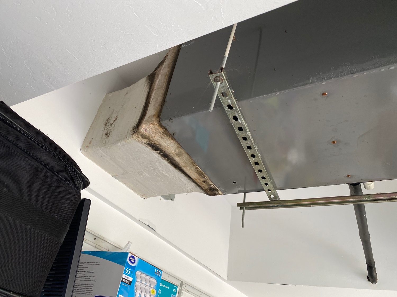 Dark staining spreading along a ceiling duct seam.