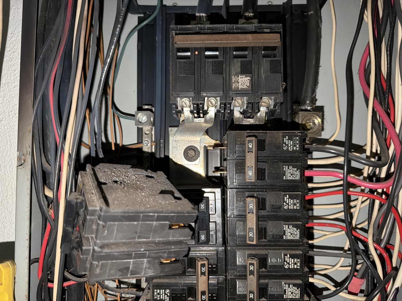 A scorched breaker still seated in the panel, its case blistered and blackened from heat.