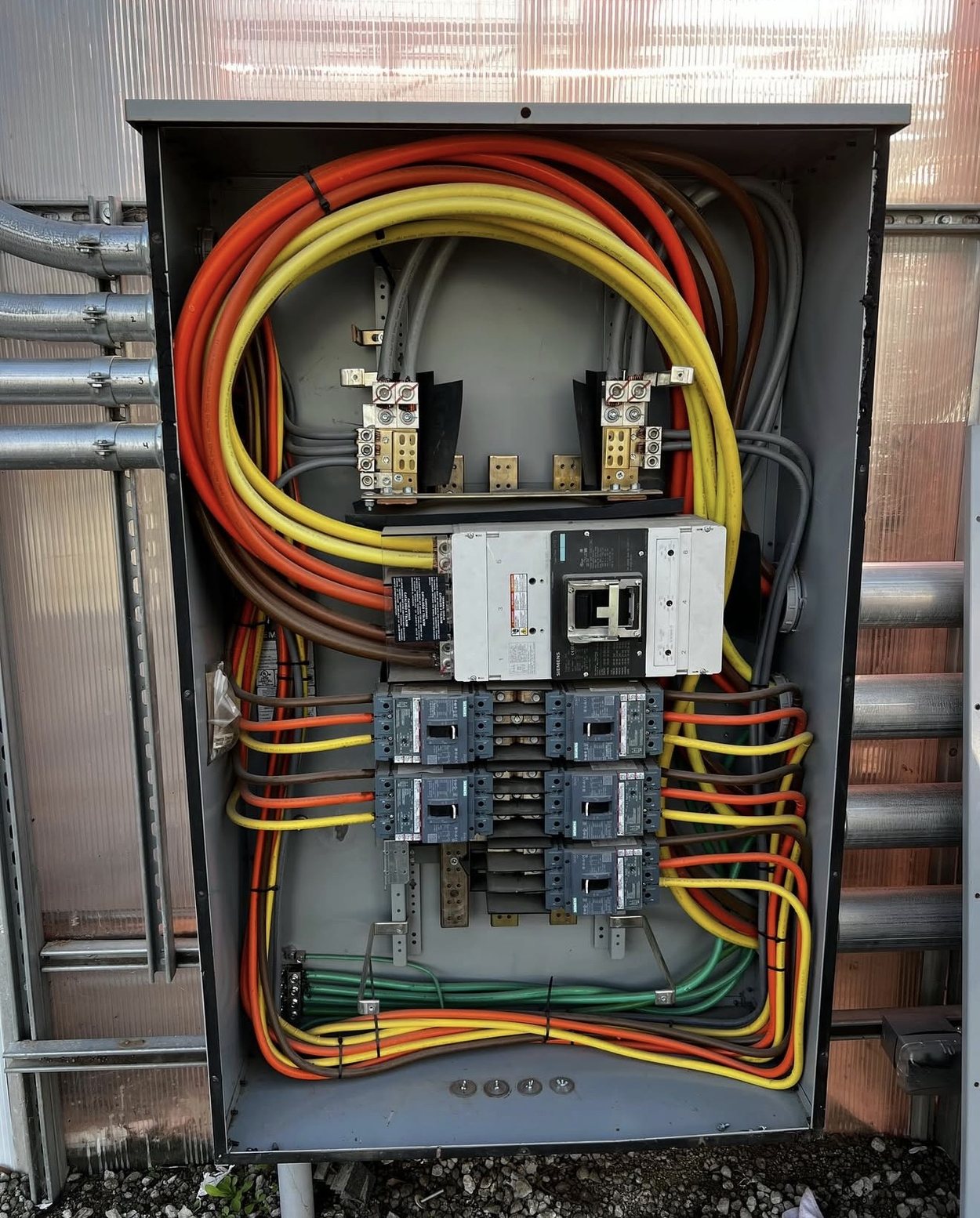 Commercial switchgear with heavy orange and yellow feeders landed on the main breaker.