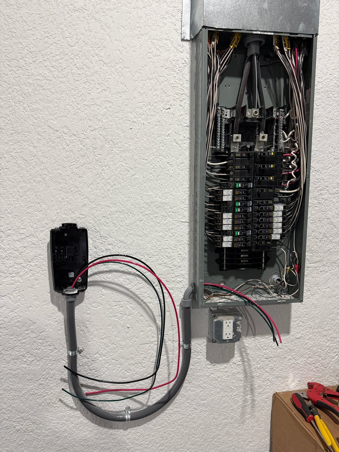 A new disconnect box and conduit run installed beside a breaker panel.