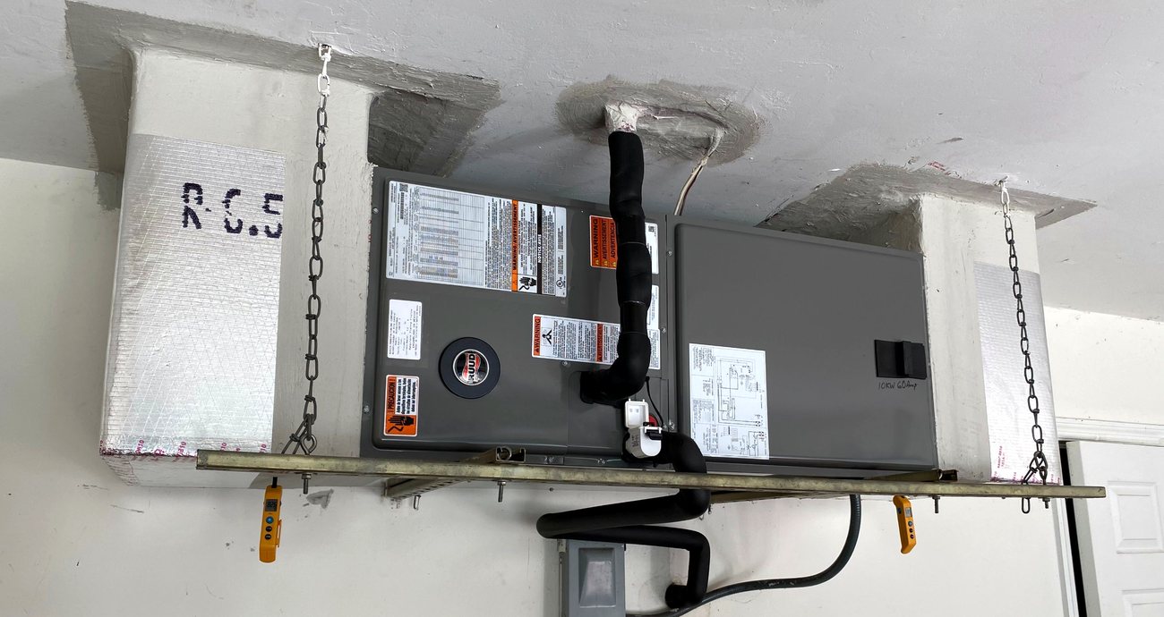 Ceiling-mounted air handler hung on threaded rod, plenums sealed on both sides.