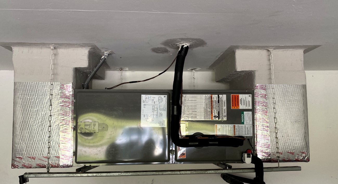 Finished ceiling-mounted air handler in a garage, chains and supports in place.