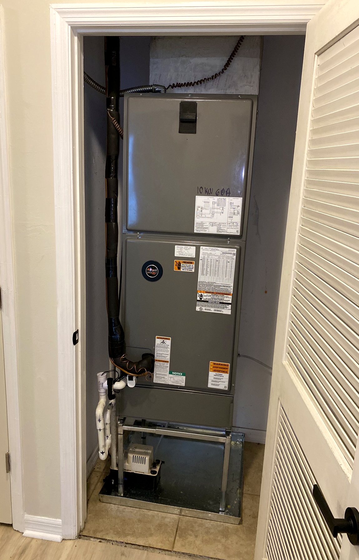 Vertical air handler installed in an interior closet behind a louvered door.