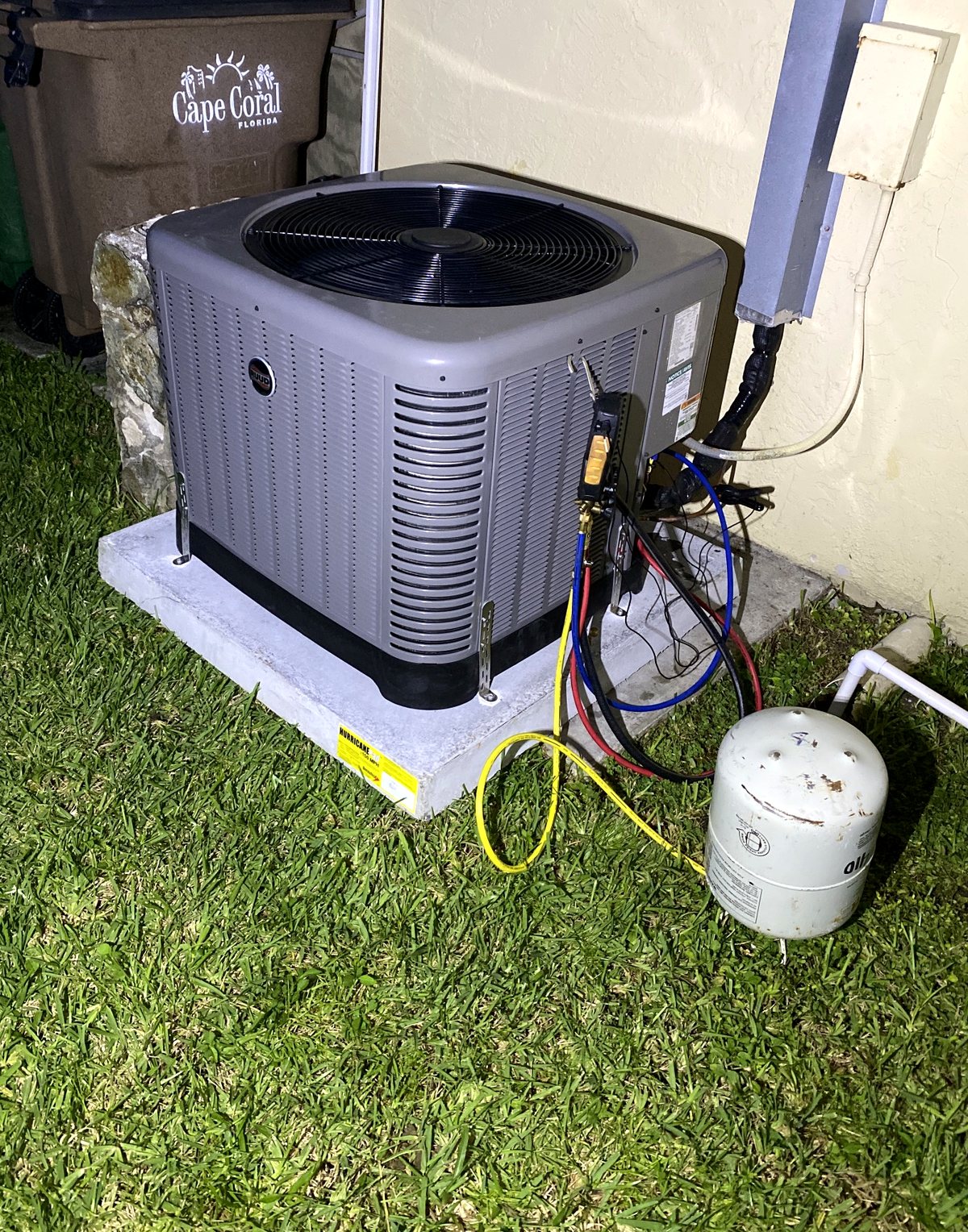 A service call after dark: digital manifold gauges connected to a condenser in a Cape Coral driveway.