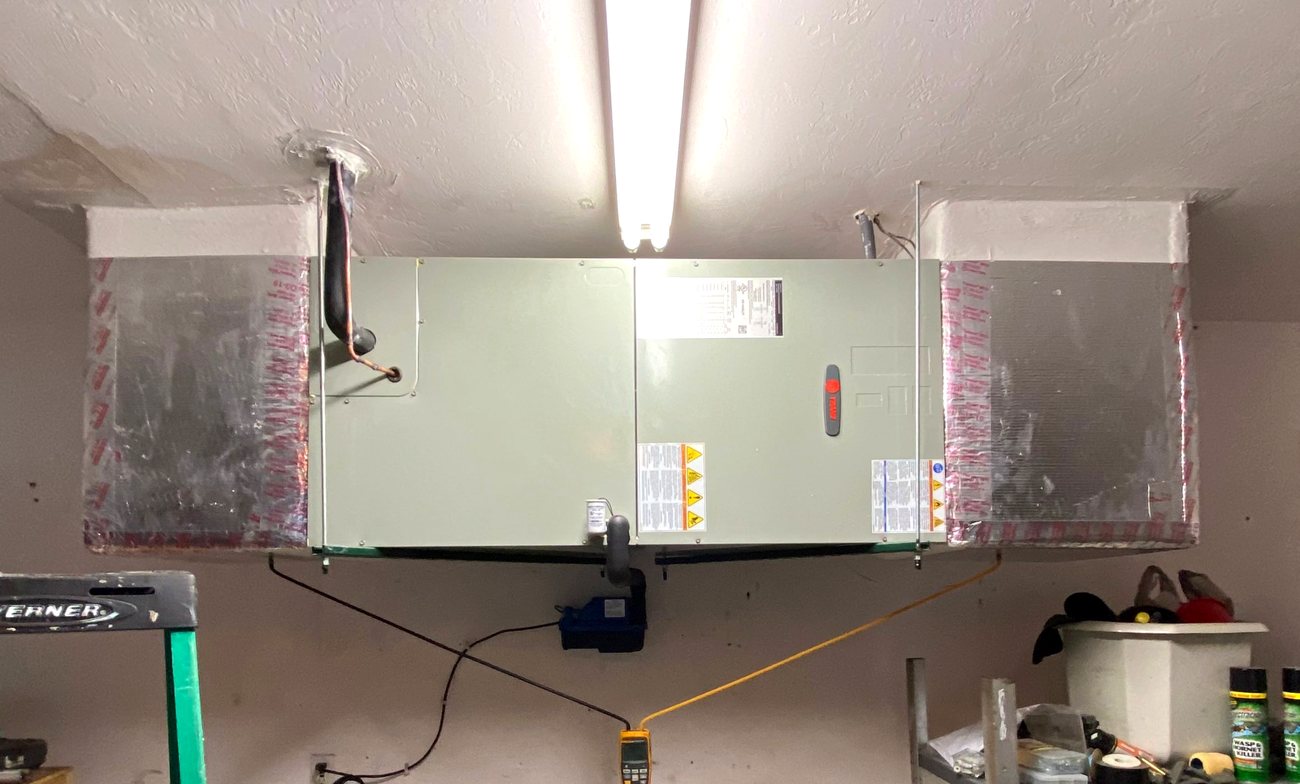 An older ceiling-mounted air handler under test, a Fluke meter reading the supply temperature.