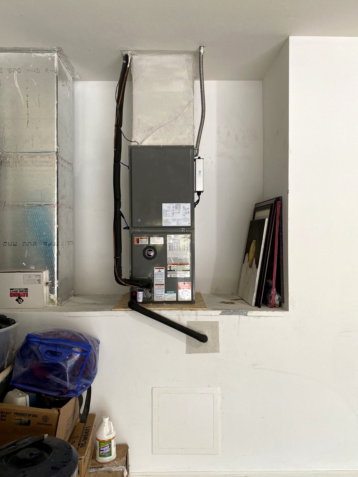 Vertical air handler set on a raised platform in a garage corner.