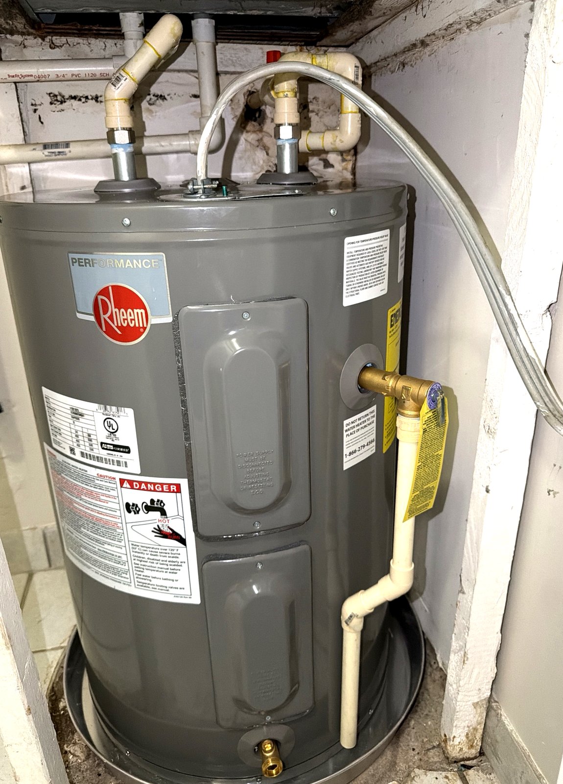 A short, wide water heater fitted into a tight interior closet.